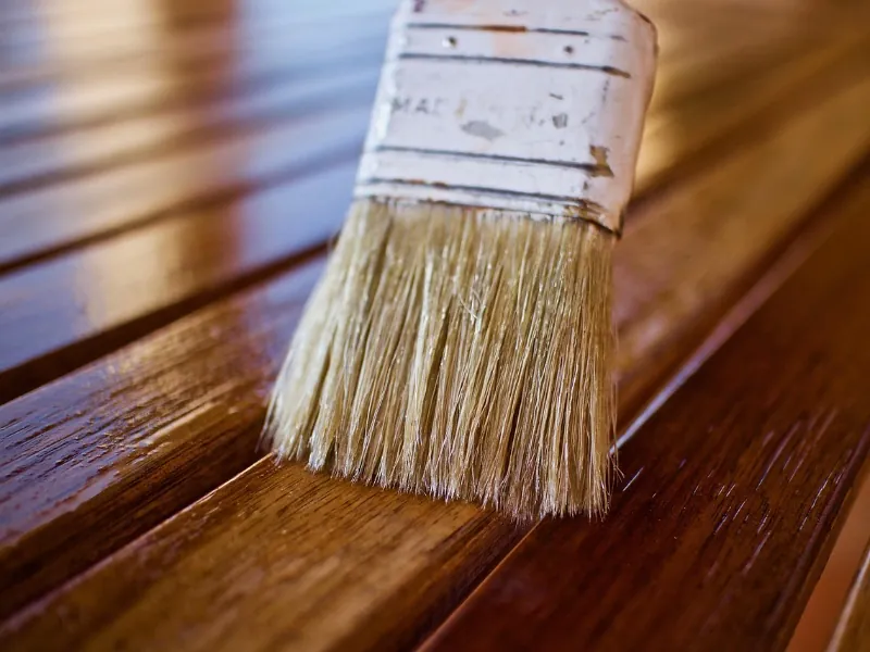 A close-up of a paintbrush carefully varnishing wood